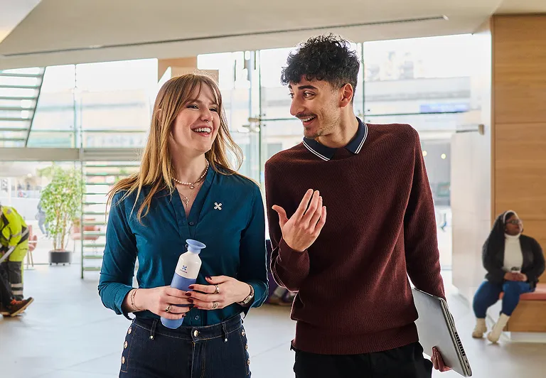 Two individuals talking to each other in a spacious lobby area.