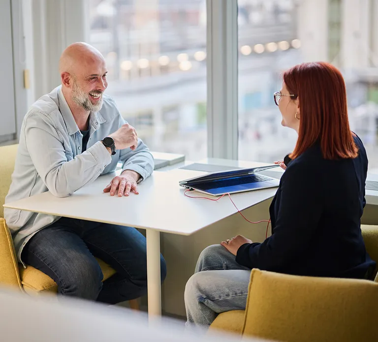 A man and woman seated at a table, actively discussing and exchanging thoughts in a friendly atmosphere.