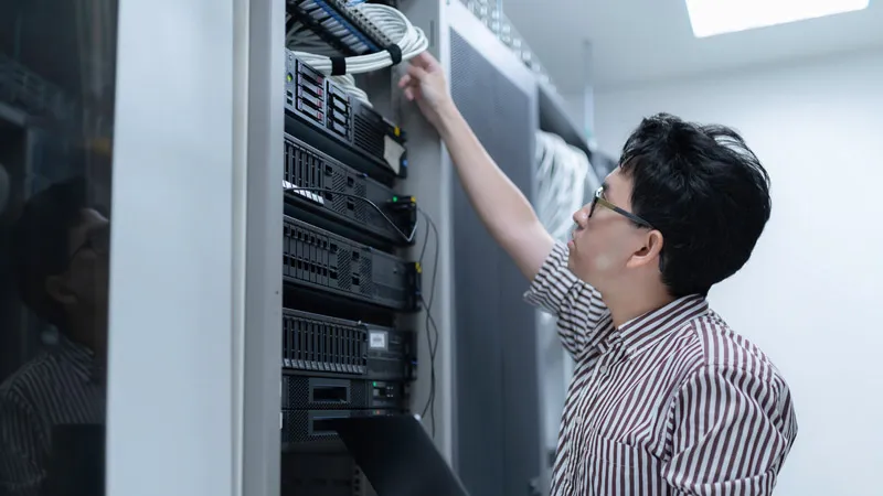 A man in a striped shirt works with data storage hardware