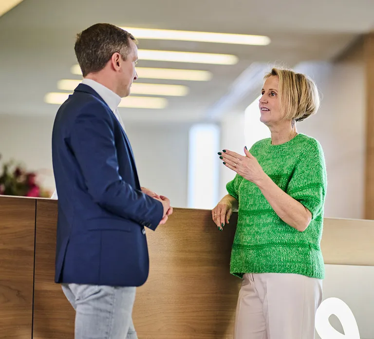 A man and woman discussing work matters in a bright office environment.