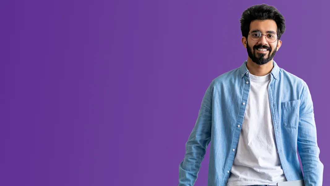 A man in a blue overshirt smiles in front of a purple background